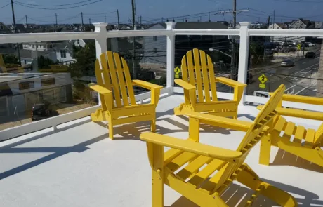 Glass Panels with PVC railings on a rooftop patio area. Yellow chairs are main focus of image.